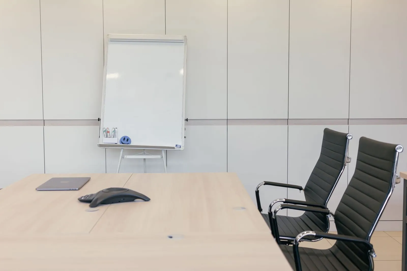 Une salle de réunion vide avant une assemblée générale, paperboard et chaises en place.